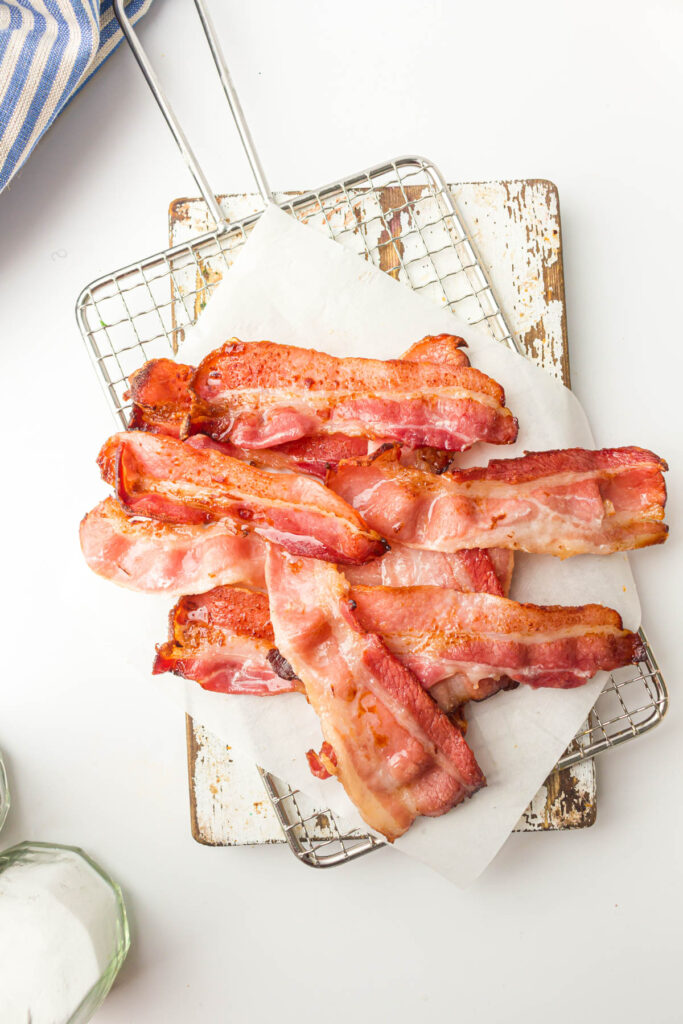 Cooked bacon on a cooling rack and parchment paper.