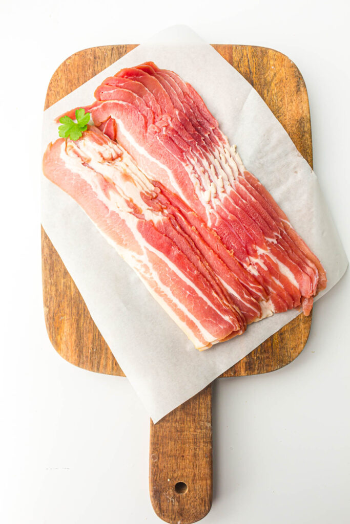 Raw bacon on a cutting board.