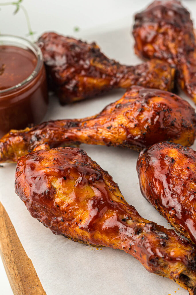 Barbecue chicken drumsticks on parchment paper.