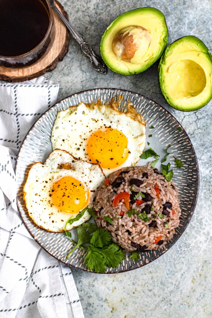 Gallo Pinto on a plate with avocado on the side.